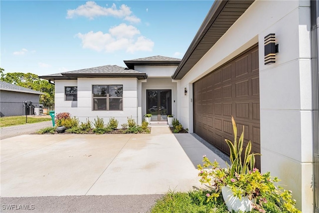 view of exterior entry featuring a garage, concrete driveway, and stucco siding