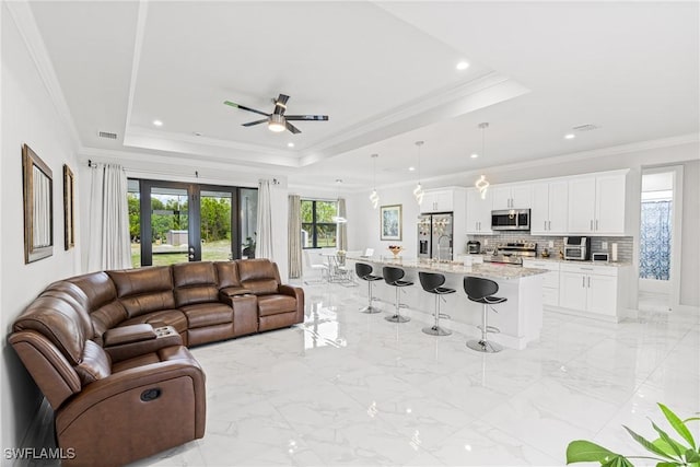 living area with marble finish floor, a tray ceiling, and french doors