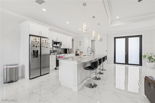 kitchen with marble finish floor, french doors, a breakfast bar area, appliances with stainless steel finishes, and ornamental molding