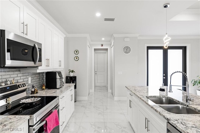 kitchen with stainless steel appliances, tasteful backsplash, visible vents, a sink, and baseboards