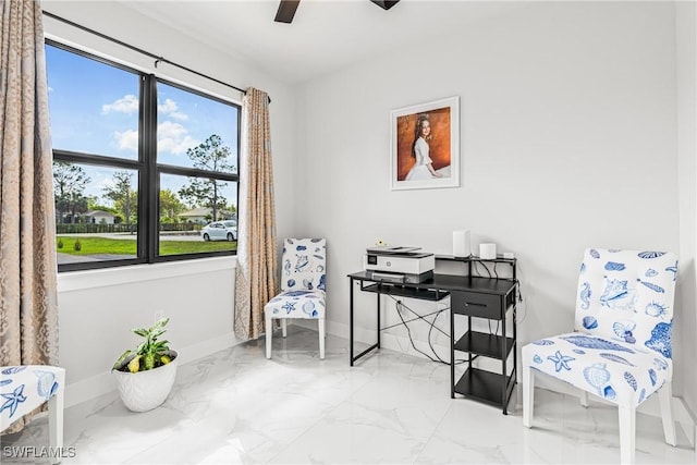 living area featuring a ceiling fan, marble finish floor, and baseboards