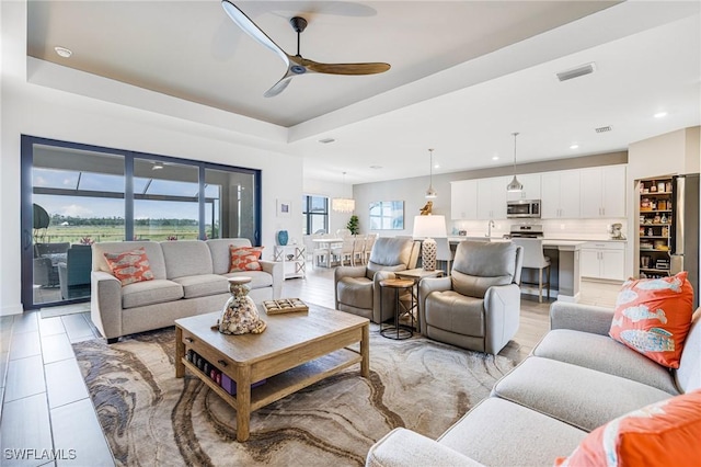 living area with visible vents, a tray ceiling, ceiling fan, and recessed lighting