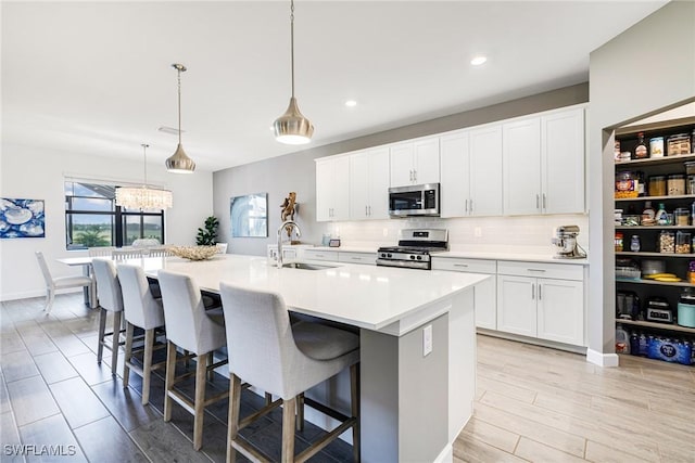 kitchen featuring a sink, a kitchen breakfast bar, light countertops, appliances with stainless steel finishes, and decorative backsplash