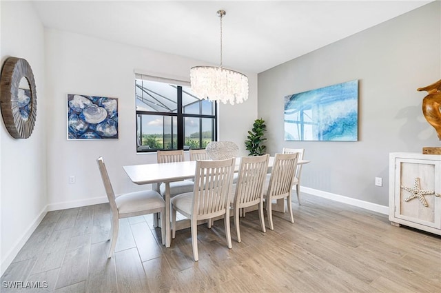 dining room featuring a chandelier, baseboards, and light wood finished floors