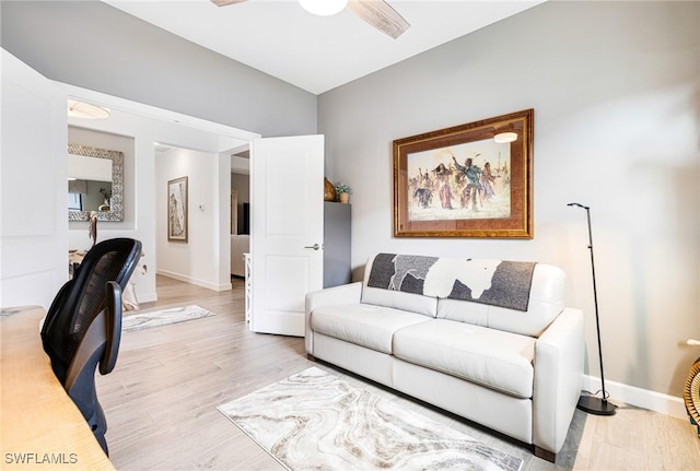 living room featuring ceiling fan, baseboards, and light wood-style floors