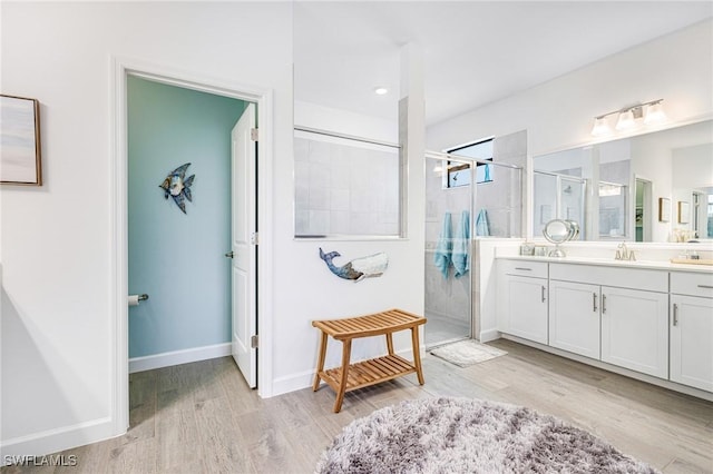 bathroom with a stall shower, wood finished floors, vanity, and baseboards