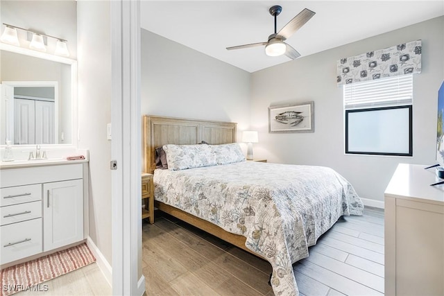 bedroom with light wood-style floors, a sink, baseboards, and a ceiling fan