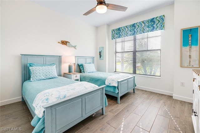 bedroom with light wood-type flooring, a ceiling fan, and baseboards