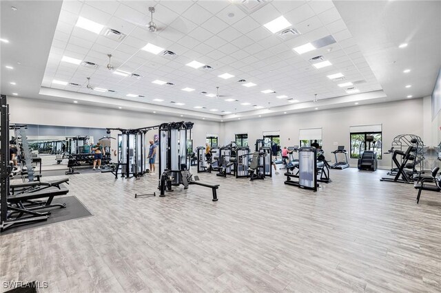 gym featuring a tray ceiling, visible vents, a towering ceiling, and wood finished floors