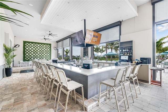 kitchen featuring ceiling fan, stone finish floor, a kitchen bar, and a healthy amount of sunlight