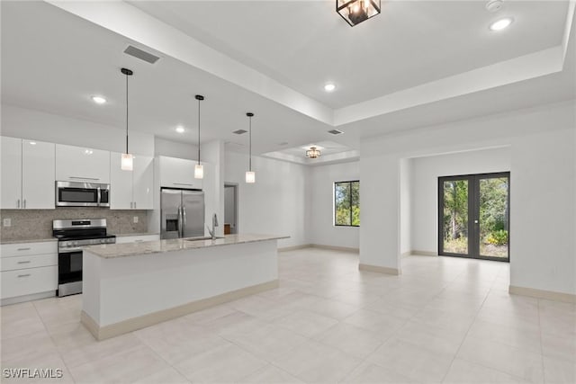 kitchen with visible vents, a sink, a tray ceiling, backsplash, and appliances with stainless steel finishes