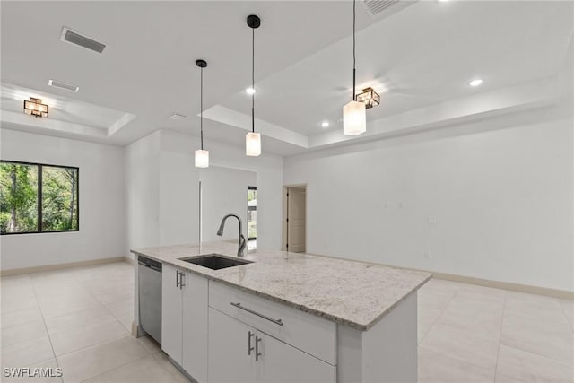 kitchen featuring visible vents, a sink, a tray ceiling, stainless steel dishwasher, and baseboards