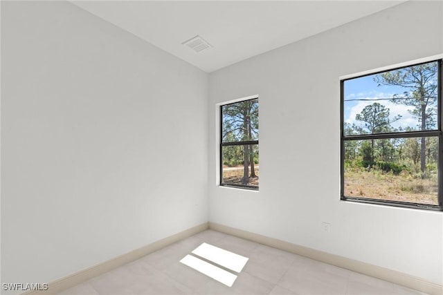 empty room with light tile patterned floors, visible vents, and baseboards