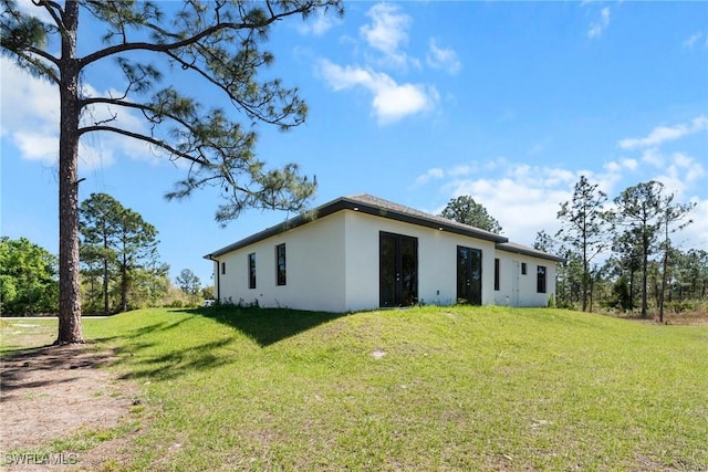 back of property with a lawn and stucco siding