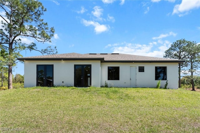 back of property with a lawn and stucco siding