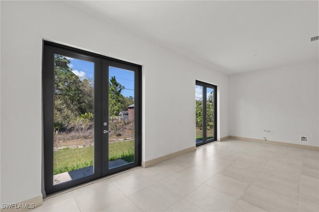 empty room featuring visible vents, french doors, and baseboards