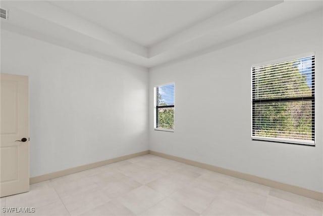 empty room featuring visible vents, baseboards, and a raised ceiling