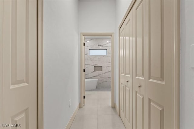 hall featuring light tile patterned flooring and baseboards