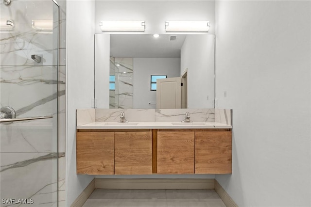 bathroom with a marble finish shower, double vanity, and a sink