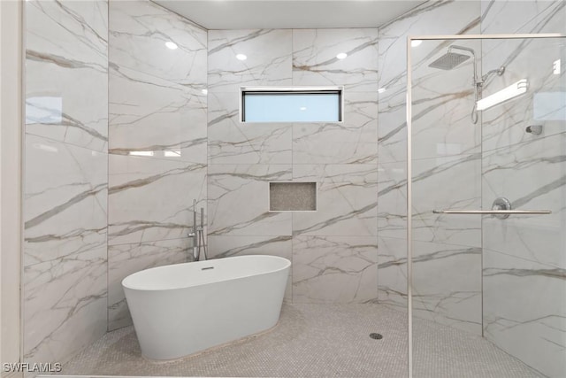 bathroom featuring a marble finish shower and a freestanding tub