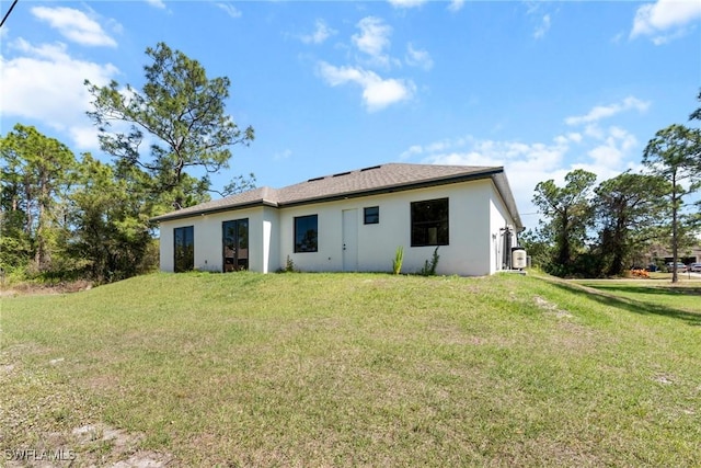 rear view of house featuring stucco siding and a lawn