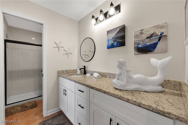 bathroom with baseboards, a shower stall, vanity, and tile patterned floors