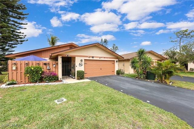 ranch-style home with a garage, aphalt driveway, fence, a front lawn, and stucco siding