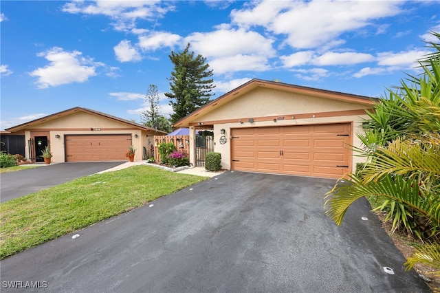 single story home with aphalt driveway, a front lawn, an attached garage, and stucco siding