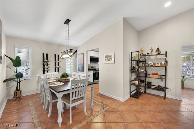 dining space with vaulted ceiling, light tile patterned flooring, and a healthy amount of sunlight