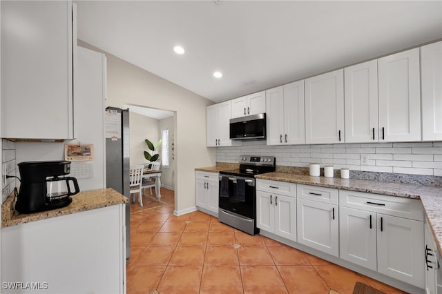 kitchen featuring light tile patterned floors, stainless steel appliances, lofted ceiling, decorative backsplash, and white cabinetry