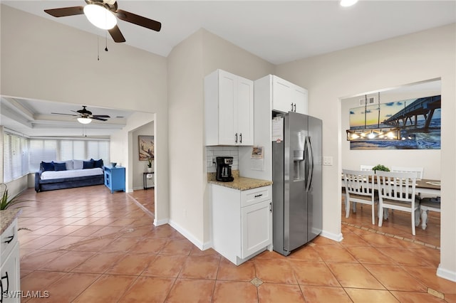 kitchen featuring light stone counters, light tile patterned flooring, white cabinetry, stainless steel fridge with ice dispenser, and decorative backsplash