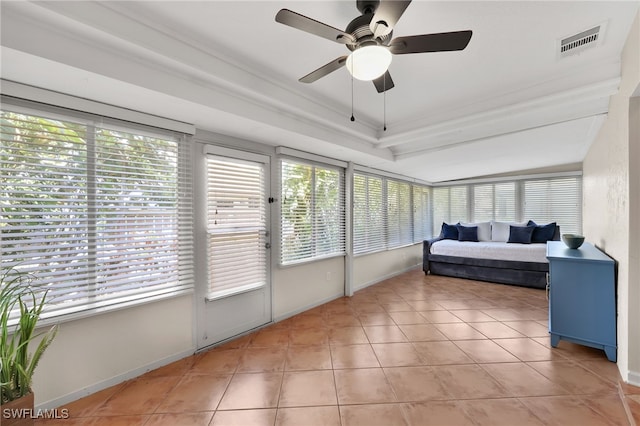 sunroom / solarium featuring a healthy amount of sunlight, ceiling fan, visible vents, and a raised ceiling