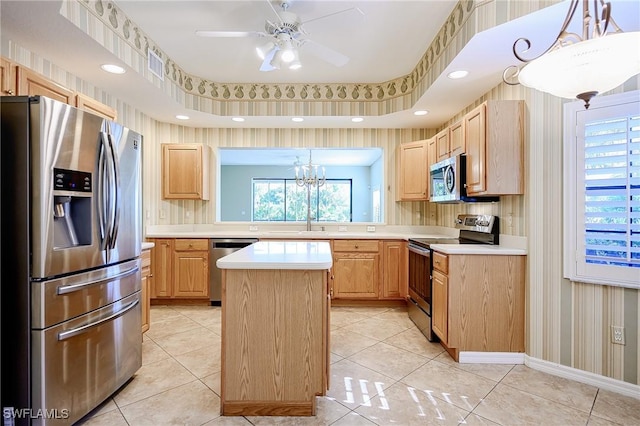 kitchen featuring stainless steel appliances, light brown cabinetry, wallpapered walls, light countertops, and a center island