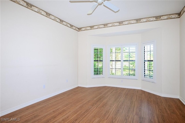 empty room with wood finished floors, baseboards, and a ceiling fan