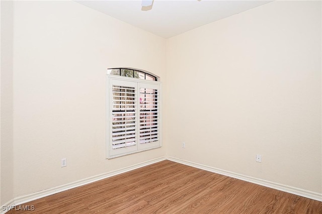 empty room featuring wood finished floors, baseboards, and a ceiling fan