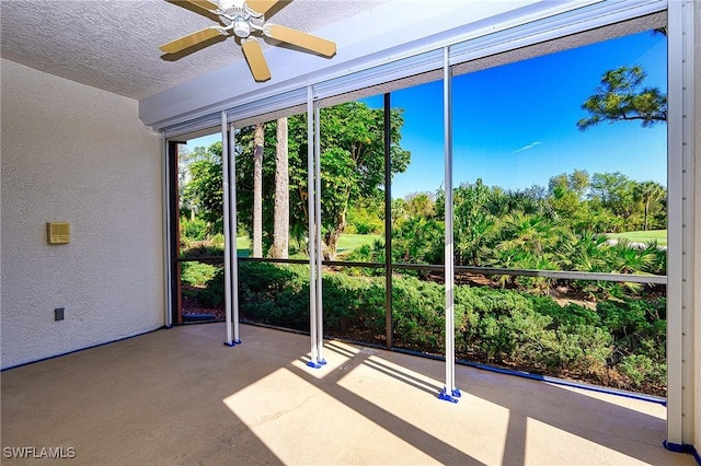 unfurnished sunroom featuring view of wooded area