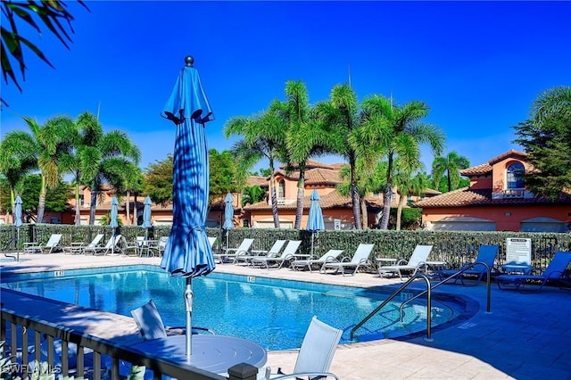 community pool with a patio area and fence