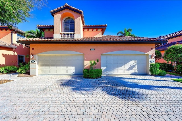 mediterranean / spanish home featuring a tiled roof, decorative driveway, and stucco siding