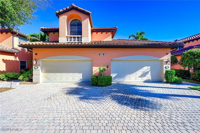 mediterranean / spanish home with decorative driveway, stucco siding, and a tiled roof
