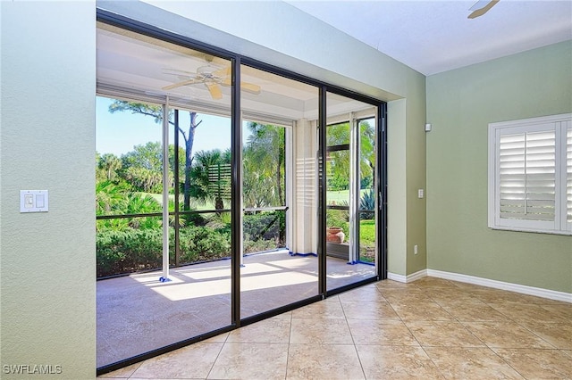 doorway with ceiling fan, plenty of natural light, tile patterned flooring, a textured wall, and baseboards