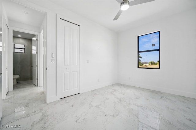 unfurnished bedroom featuring ceiling fan, marble finish floor, a closet, and baseboards