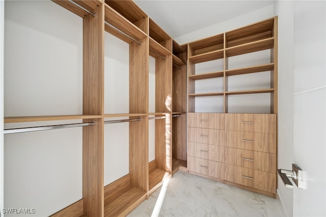 walk in closet featuring marble finish floor