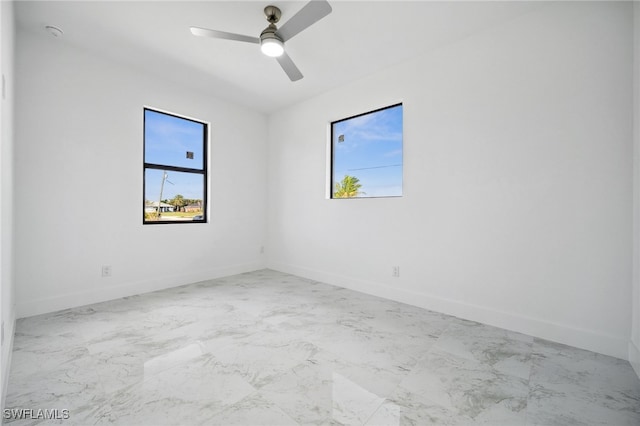 empty room featuring marble finish floor, ceiling fan, and baseboards