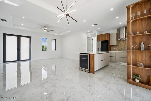 kitchen with wine cooler, visible vents, wall chimney range hood, modern cabinets, and a raised ceiling