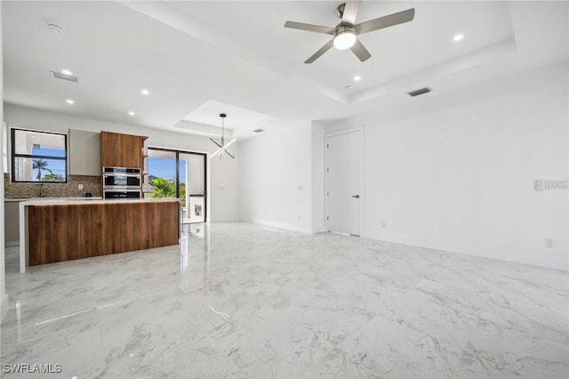 kitchen with double oven, a tray ceiling, plenty of natural light, and light countertops