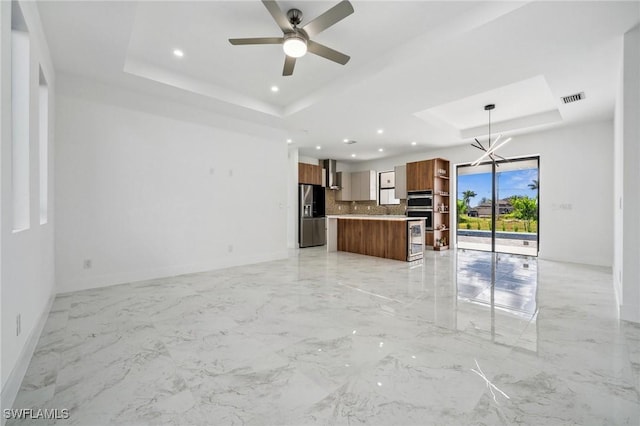 unfurnished living room featuring a tray ceiling, marble finish floor, visible vents, and baseboards