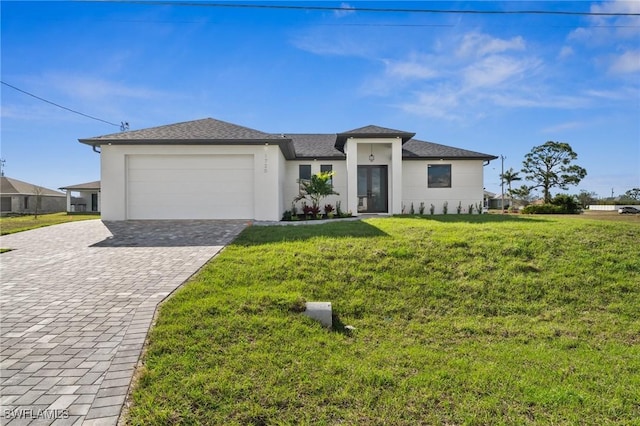 prairie-style house with decorative driveway, an attached garage, stucco siding, and a front yard