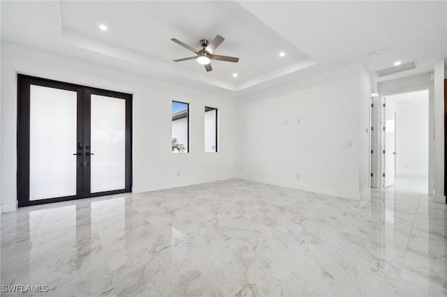 spare room with a tray ceiling, french doors, marble finish floor, recessed lighting, and baseboards