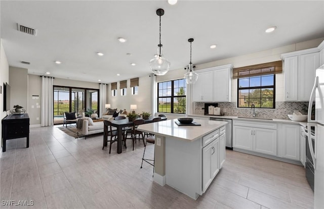 kitchen featuring a sink, a kitchen island, visible vents, light countertops, and decorative backsplash