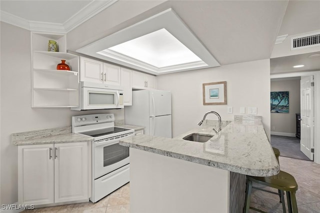 kitchen featuring a sink, white appliances, a peninsula, a breakfast bar area, and crown molding